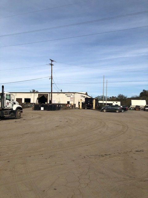 A truck is parked in a dirt lot in front of a building.