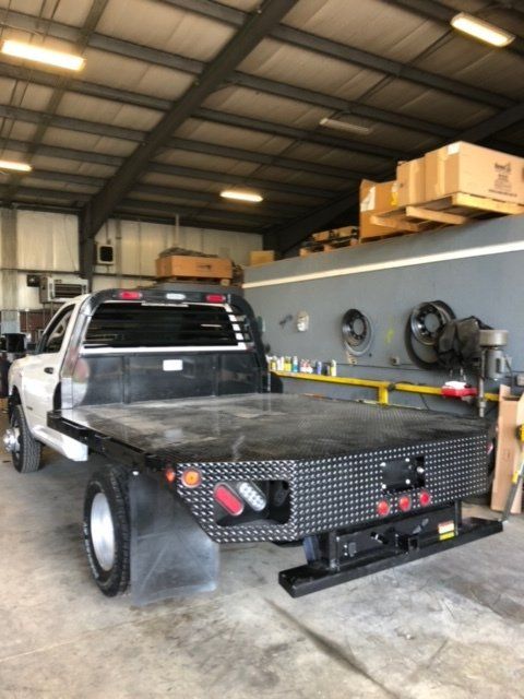A truck with a flat bed is parked in a garage