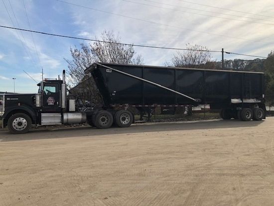 A black dump truck is parked on a dirt road