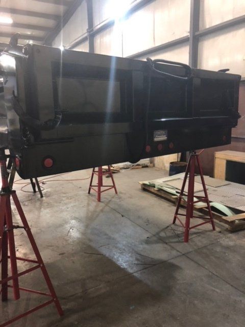 A large piece of metal is sitting on red stands in a warehouse.
