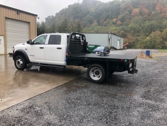 A white flatbed truck is parked in a parking lot.