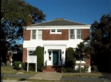 A large brick house with a white trim and a green door