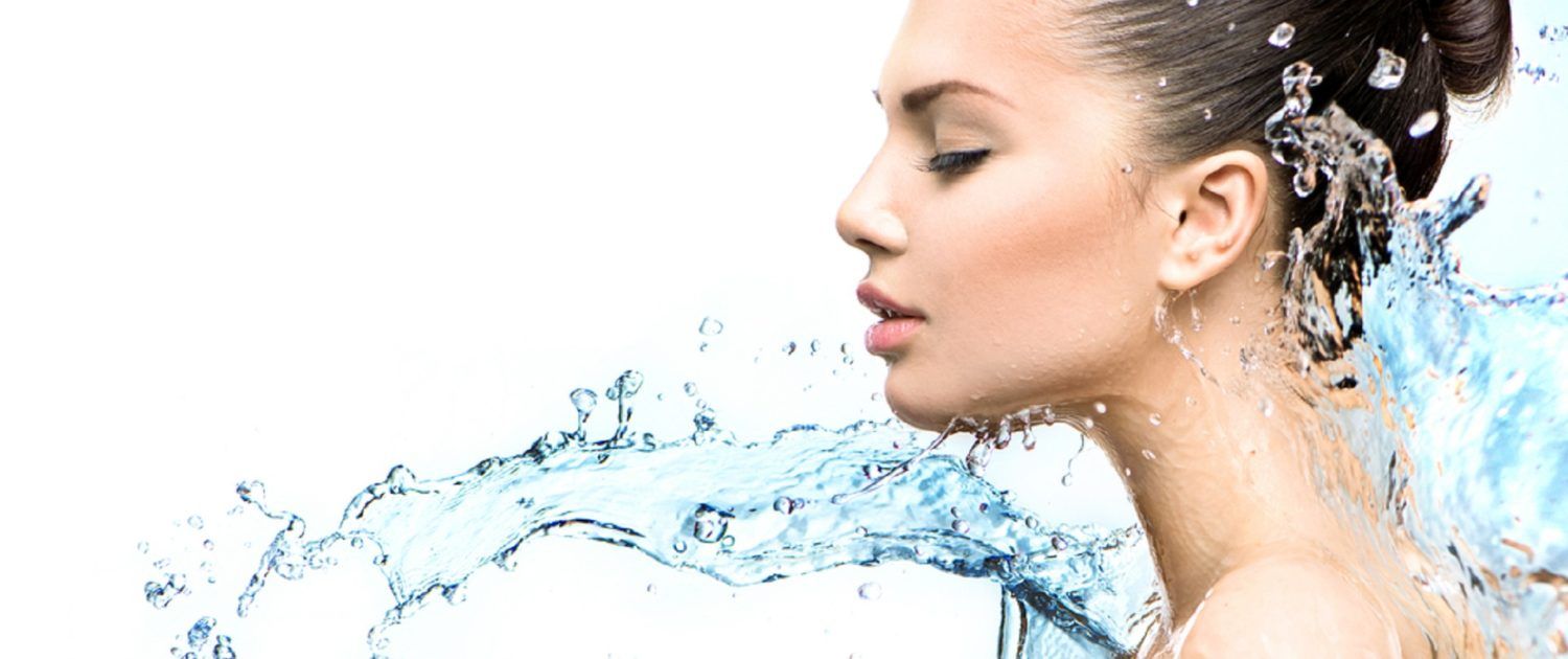 Eine Frau duscht und Wasser spritzt ihr ins Gesicht.
