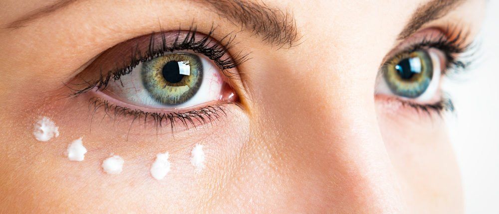 Eine Nahaufnahme der Augen einer Frau mit Augencreme darauf.