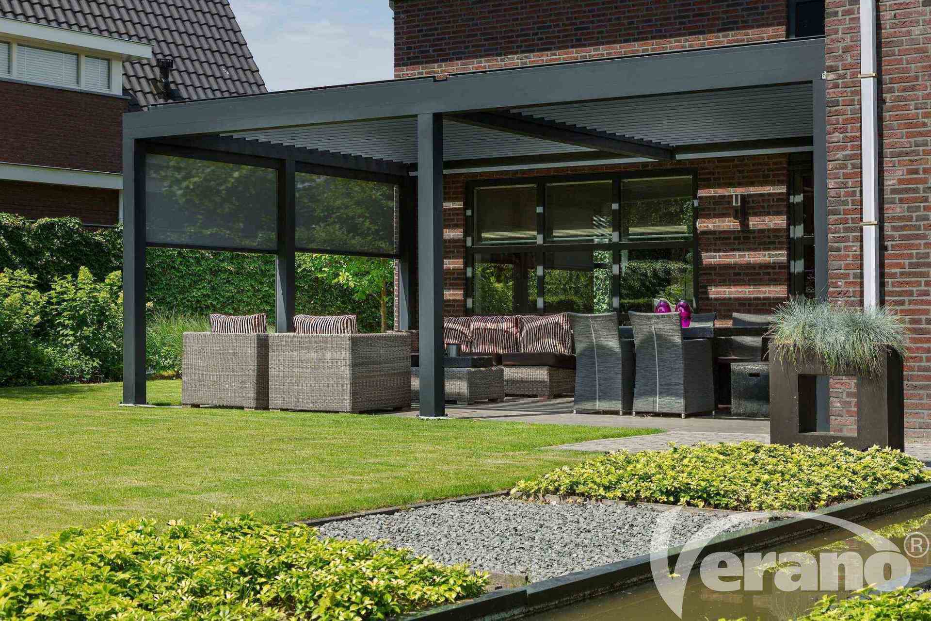 Een patio met een pergola en een bakstenen gebouw op de achtergrond