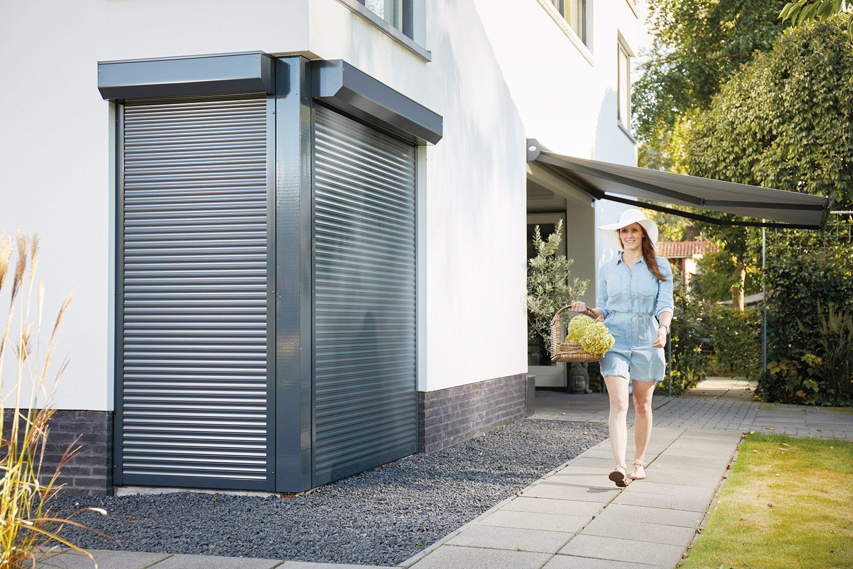 Een vrouw loopt over het trottoir naast een garagedeur.