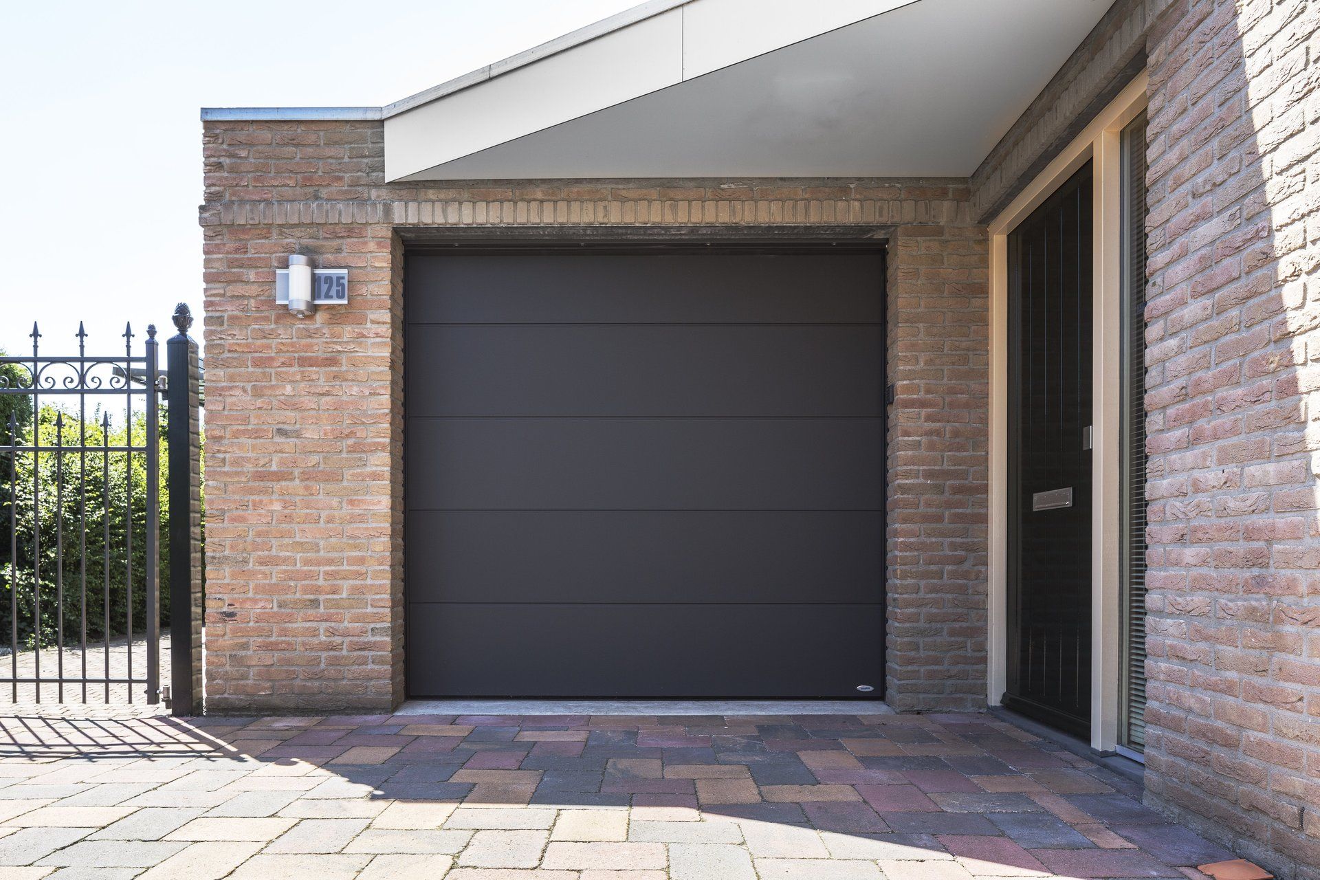 Een bakstenen gebouw met een zwarte garagedeur