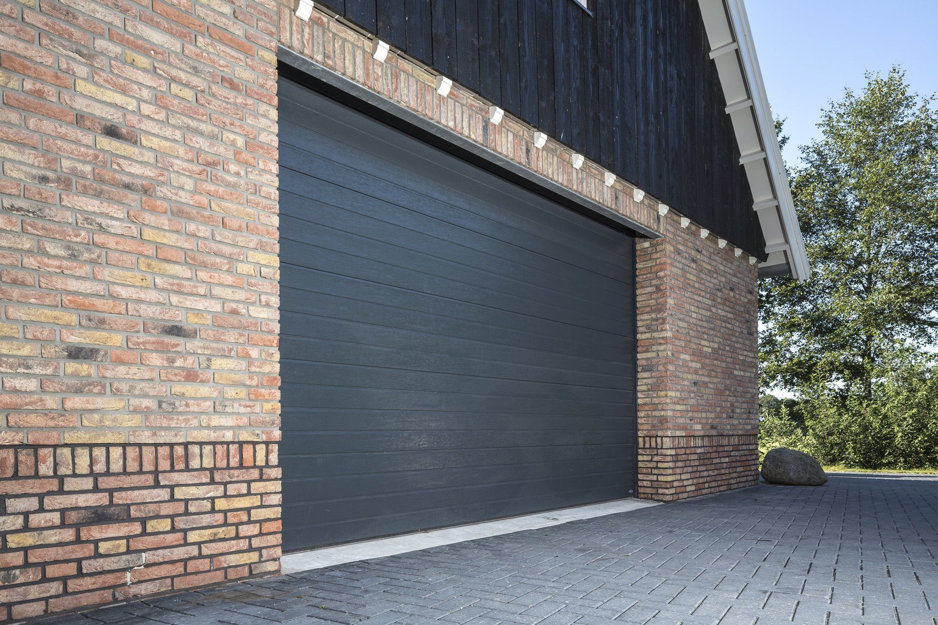 Een bakstenen gebouw met een zwarte garagedeur