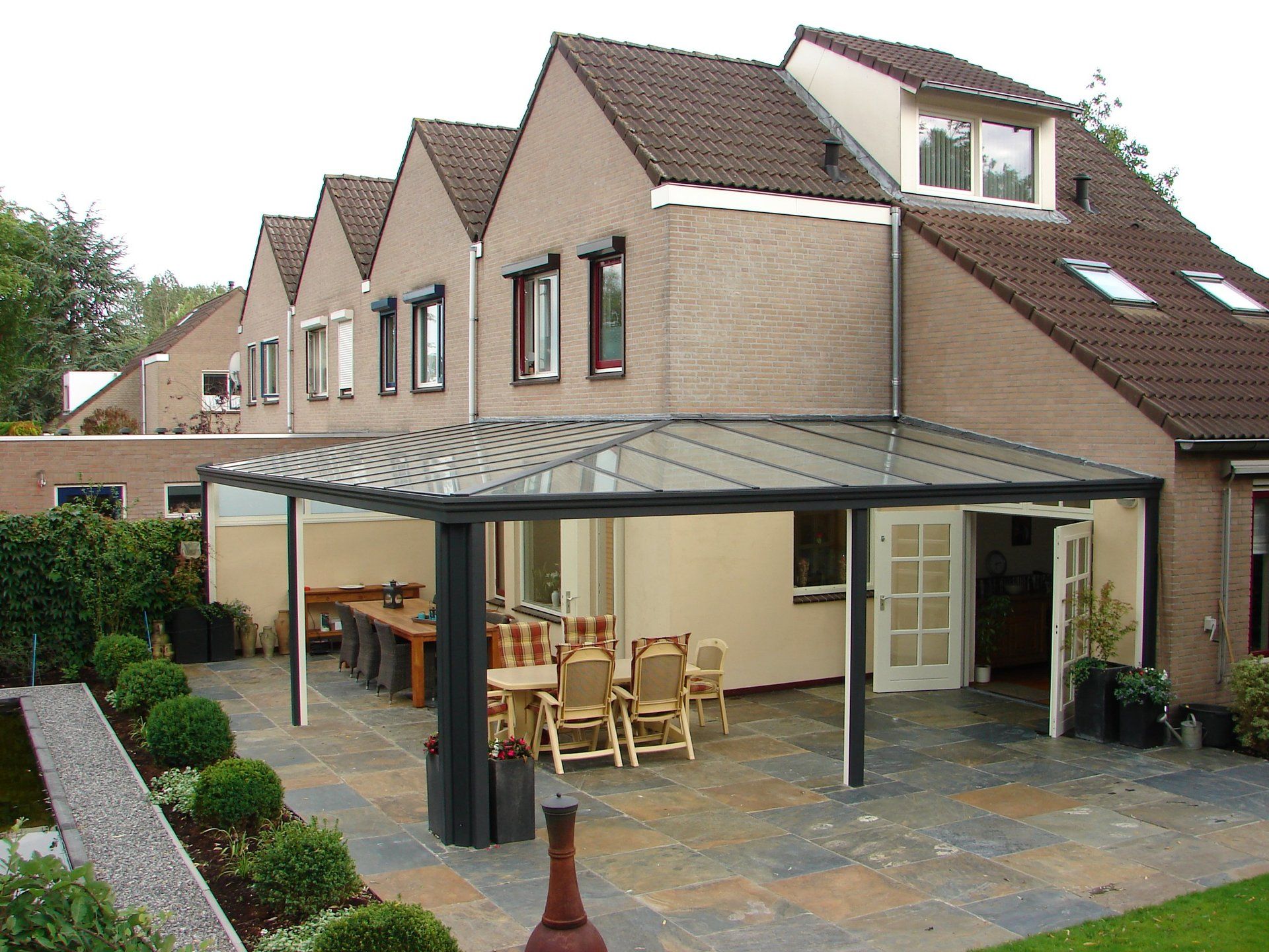 Een groot huis met een overdekt terras met een tafel en stoelen