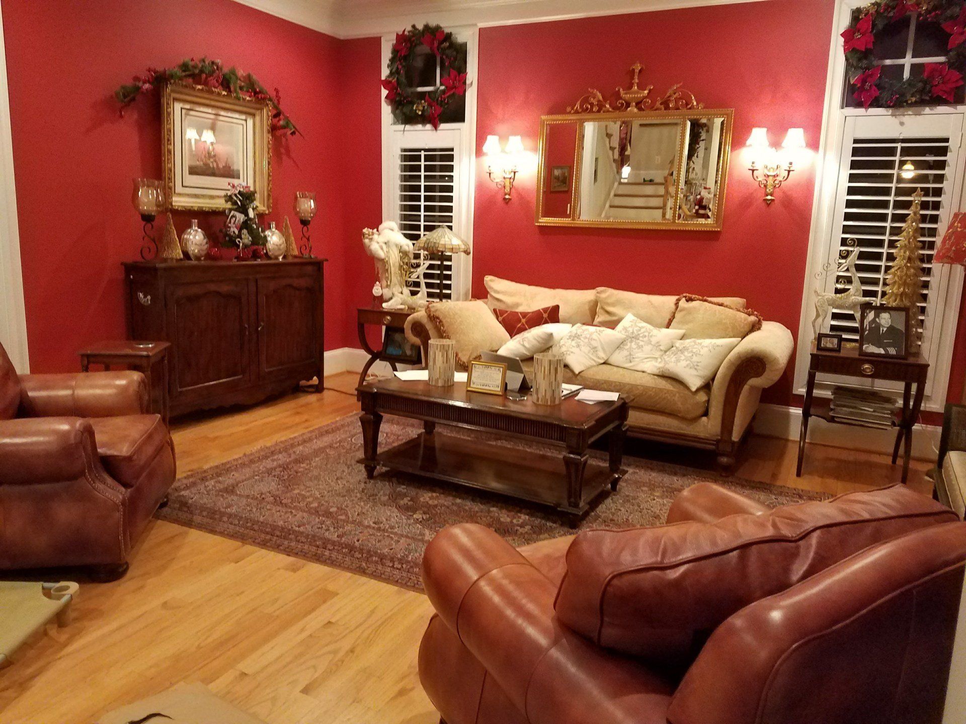 Living room with red walls, leather furniture, and Christmas decorations.