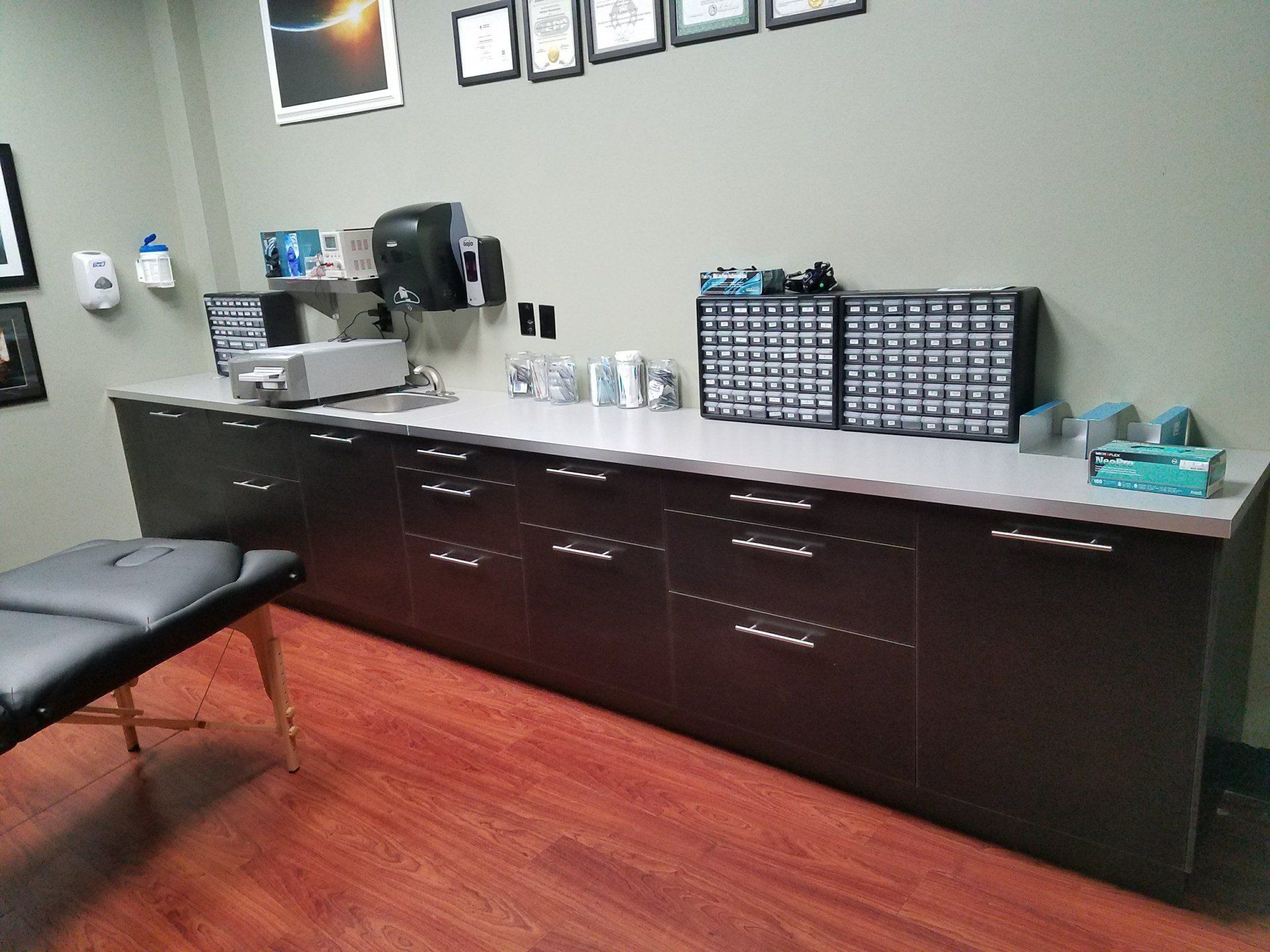 Examination room with brown cabinets, a medical bed, and supplies.
