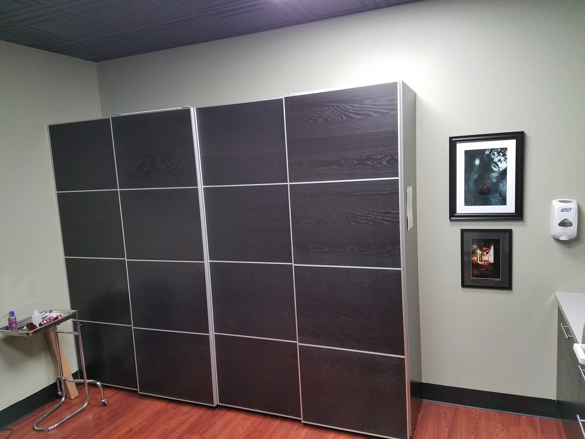 IKEA PAX wardrobe, medical exam room with framed art, hand sanitizer, and a small side table.