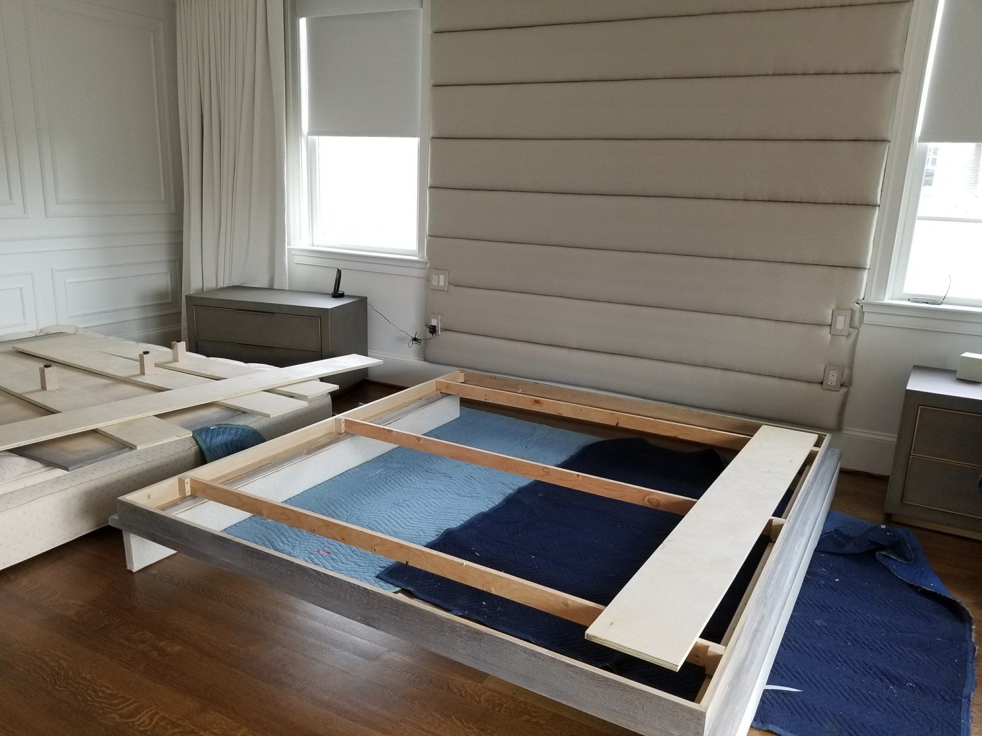 Bedroom with a bed frame, headboard, and two disassembled bed sections; a rug is partially visible.