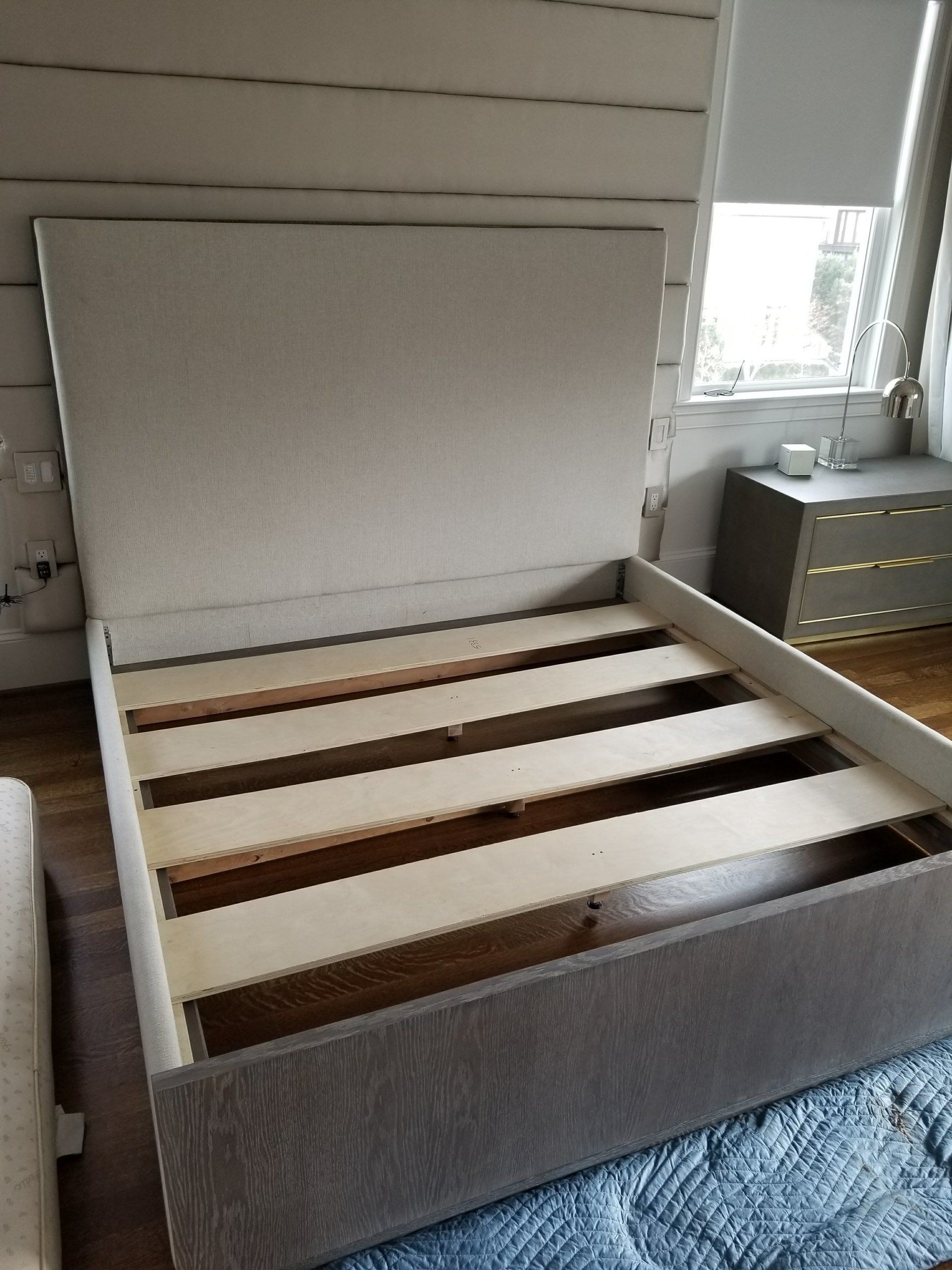 A bed frame is sitting in a room next to a window.