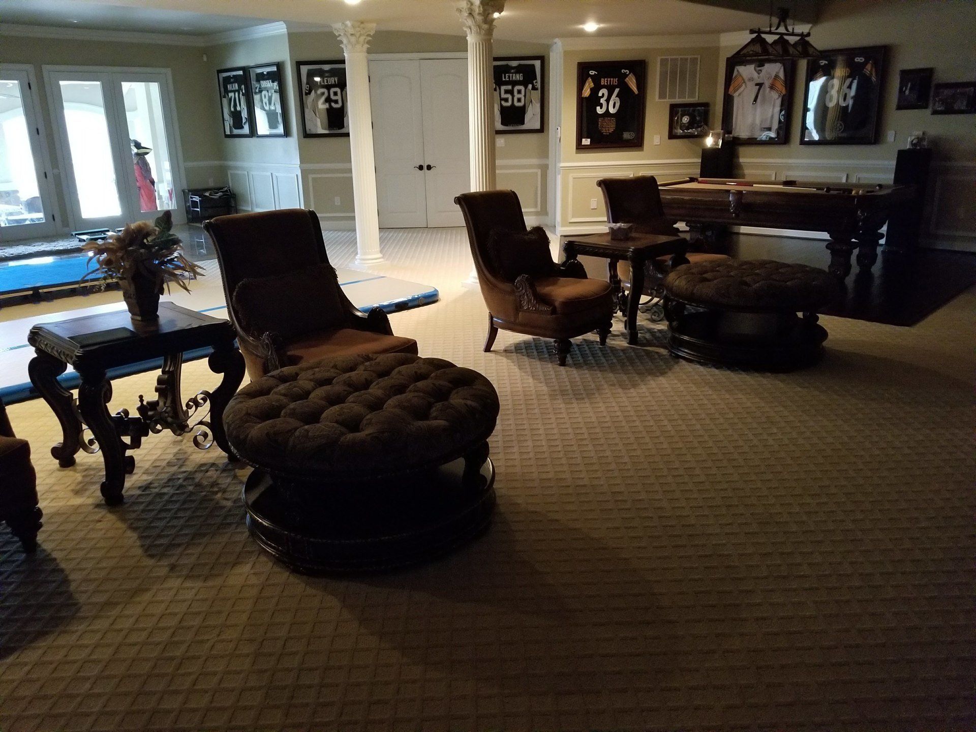A dimly lit den with seating, decor, and framed sports jerseys on the wall.