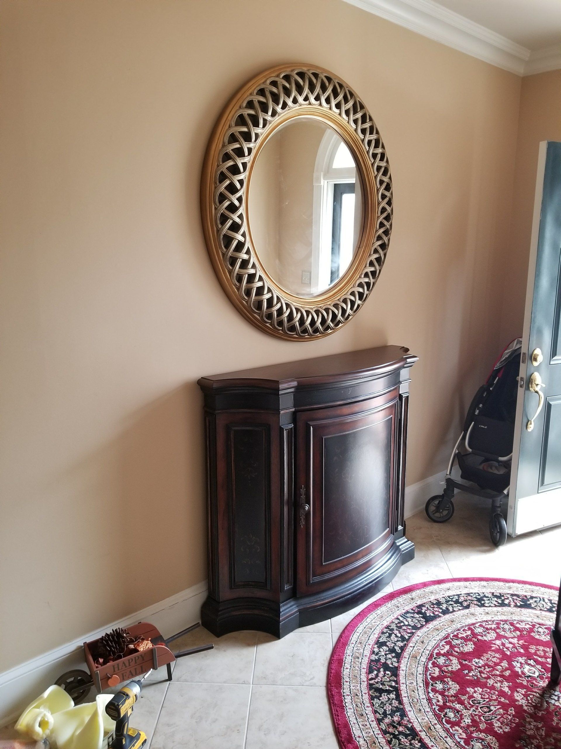 A round mirror is hanging on a wall above a dresser in a hallway.
