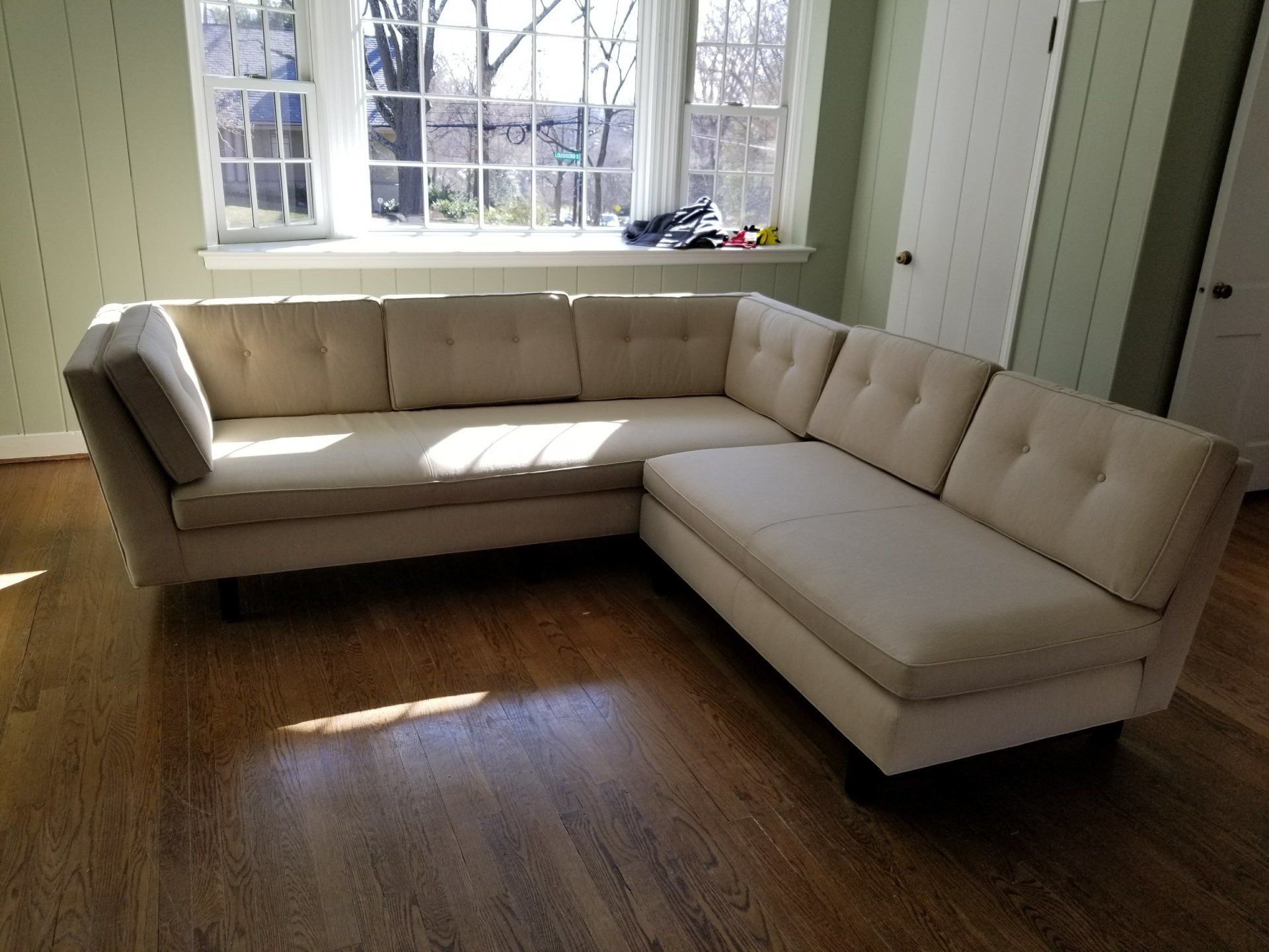 fabric creme colored corner couch under a window by furniture assembly team
