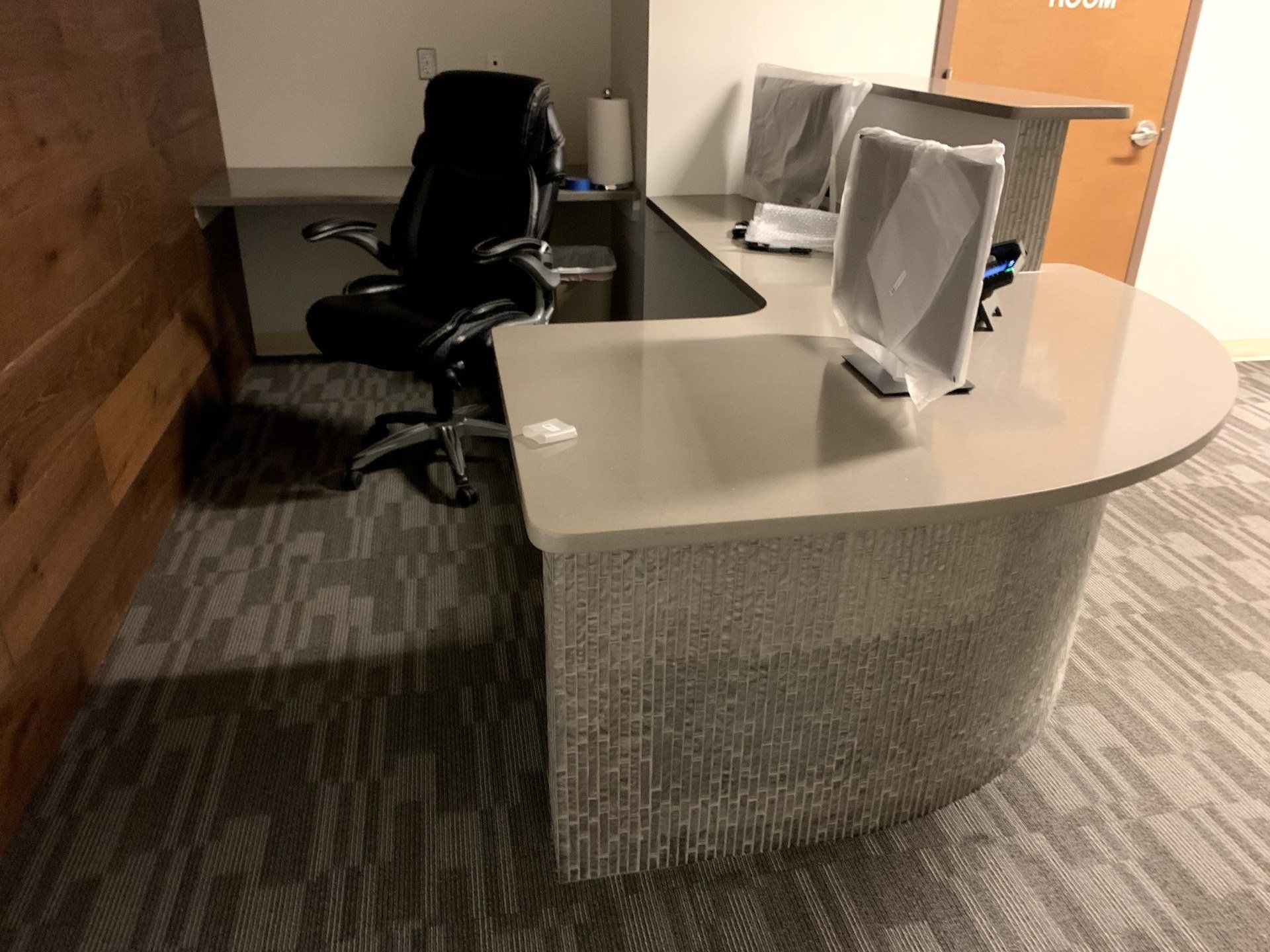 gray textured corner desk with a black office chair by furniture assembly team