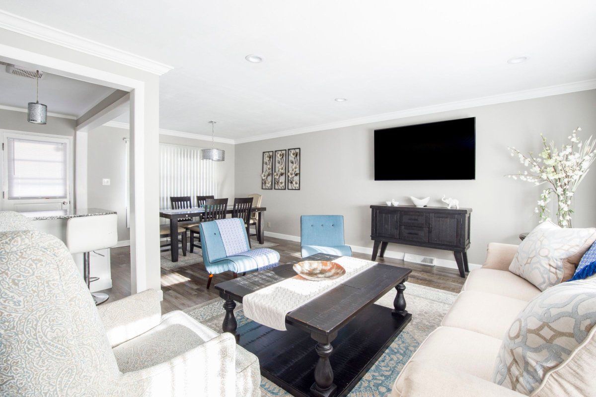 Living room with gray walls, TV, black table, and dining area.