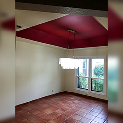 Dining room with a deep red recessed ceiling, a tiered chandelier, off-white walls, and brown tiled flooring.