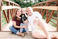 A family is posing for a picture on a bridge.