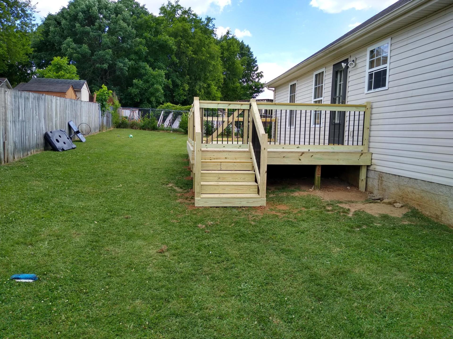 A wooden deck with stairs is in the backyard of a house.