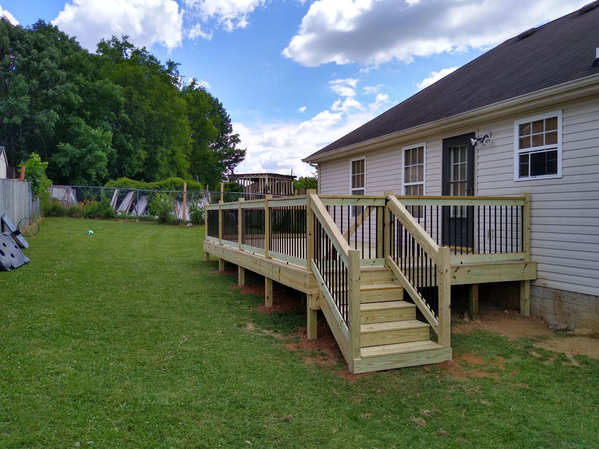 A wooden deck with stairs is in the backyard of a house.
