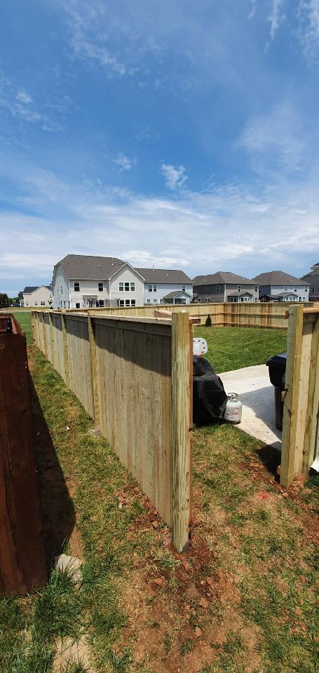A wooden fence in a backyard with houses in the background.