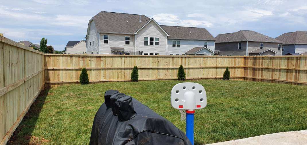 There is a basketball hoop in the backyard of a house.