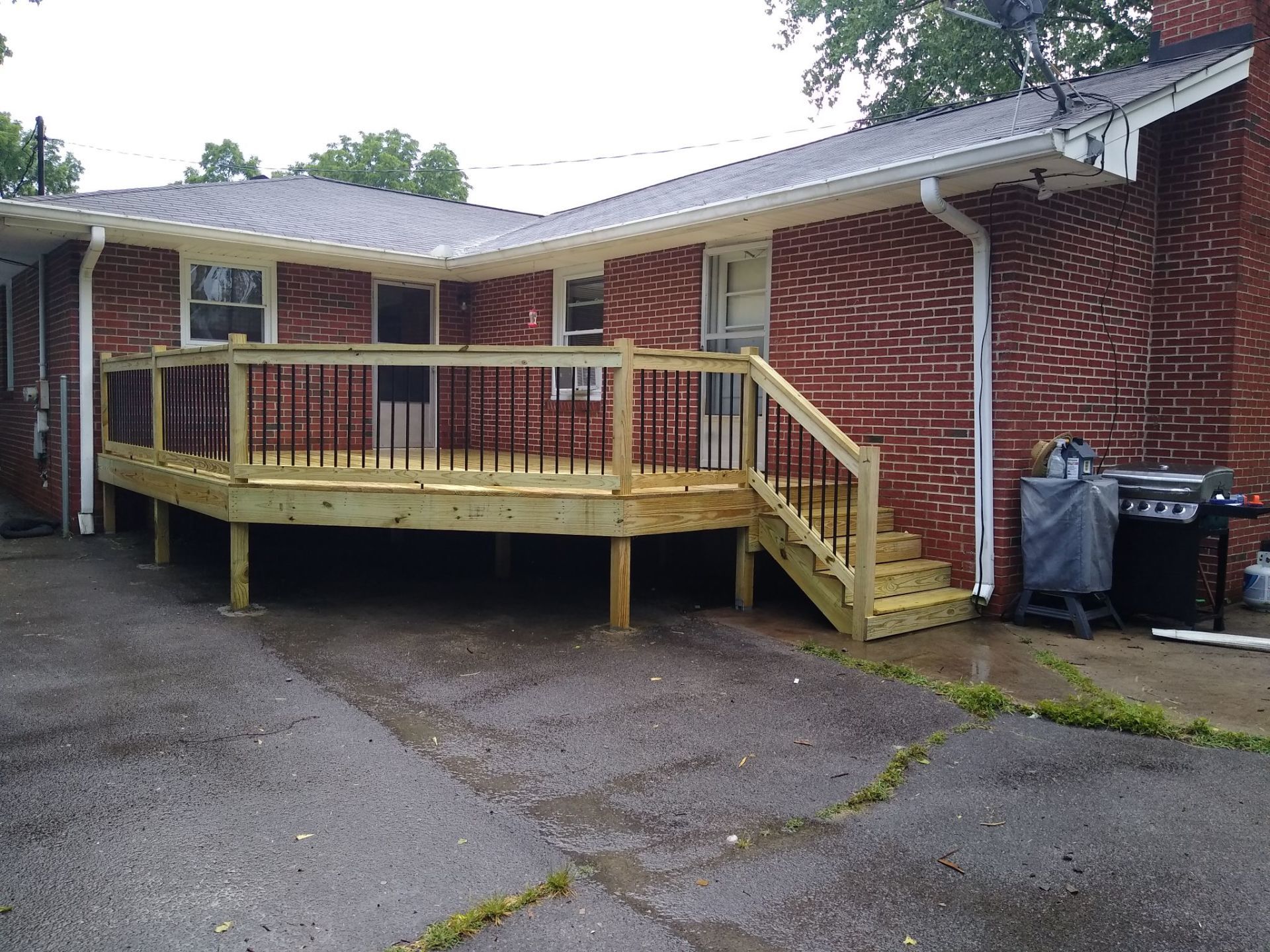 A brick house with a wooden deck and stairs in front of it.