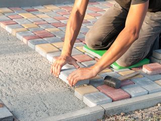 Masonry Construction — Construction Worker Laying Sidewalk Tiles in the Yard of the House in Louisville, KY Masonry Construction — Construction Worker Laying Sidewalk Tiles in the Yard of the House in Louisville, KY