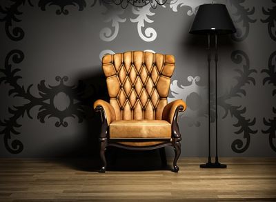 An antique chair against a black wall next to a modern black lamp