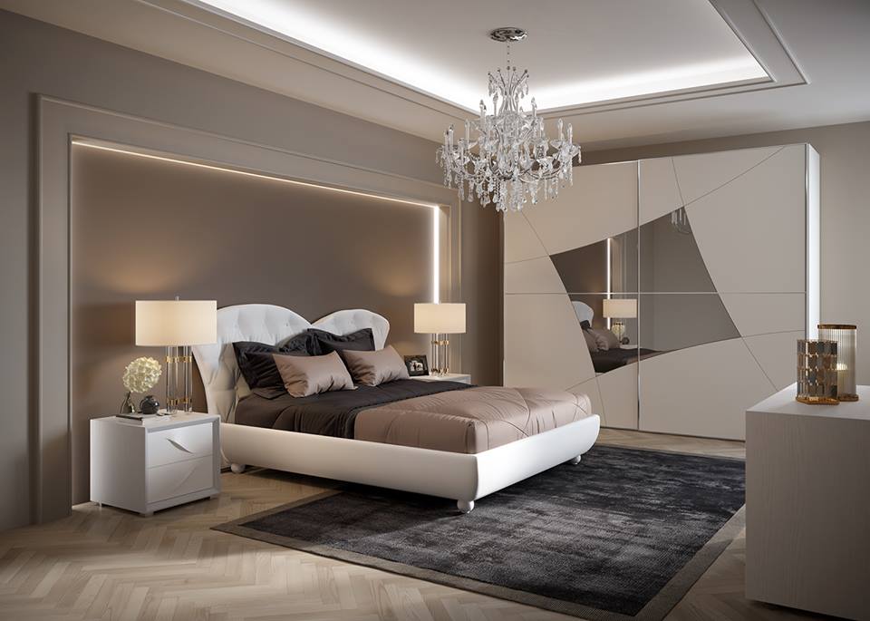 Elegante camera da letto con mobili bianchi, dettagli grigi e un lampadario di cristallo.