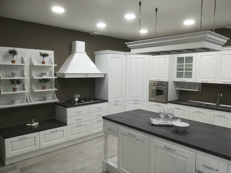 Cucina bianca con isola, ripiani neri ed elettrodomestici in acciaio inossidabile.