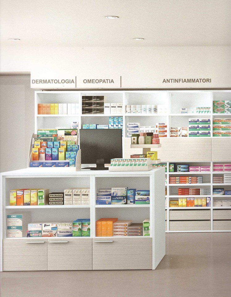 Interno di una farmacia con scaffali pieni di medicinali e un bancone con un computer.