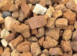 Pile of assorted brown and tan rocks, with one white stone near the top