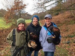 three people in autumn and a man with a hawk on his arm