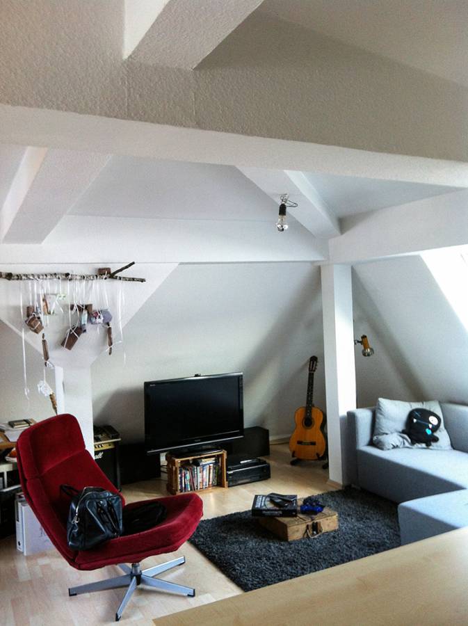 A living room with a couch a chair a television and a guitar