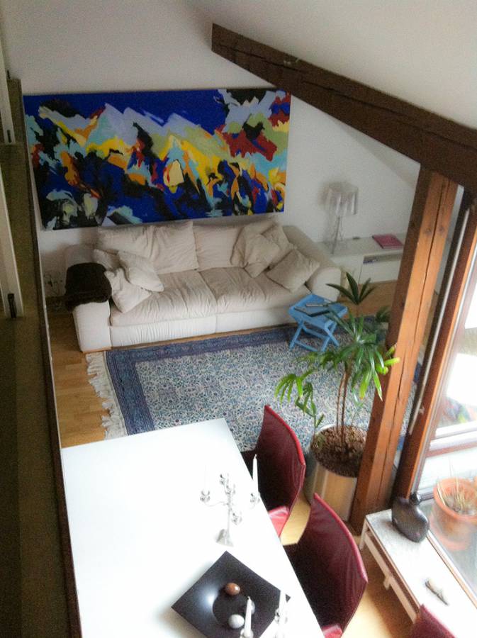 A living room with a large painting on the wall above the couch