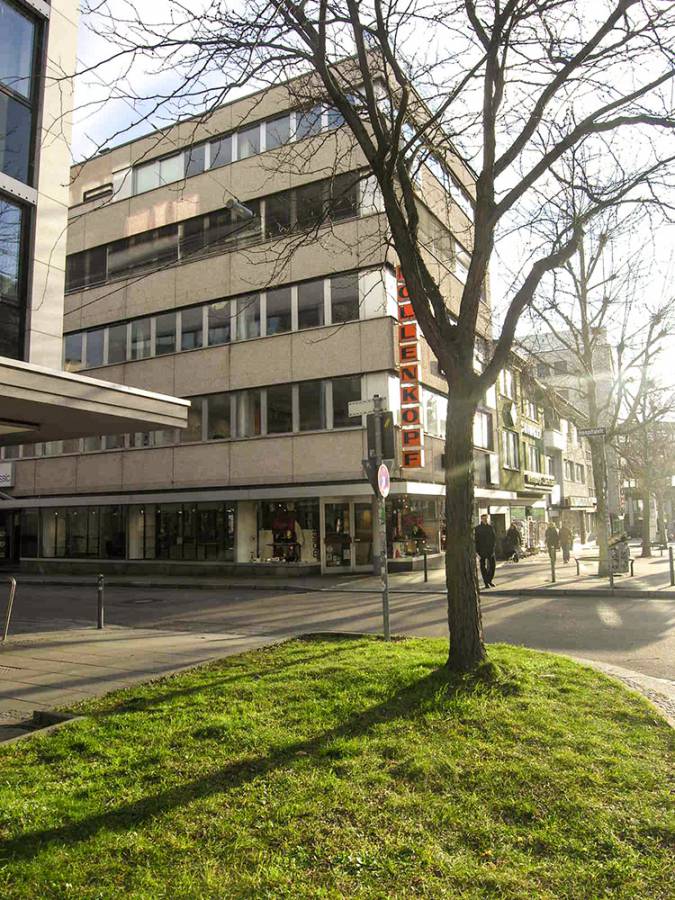 A large building with a lot of windows is surrounded by trees and grass.
