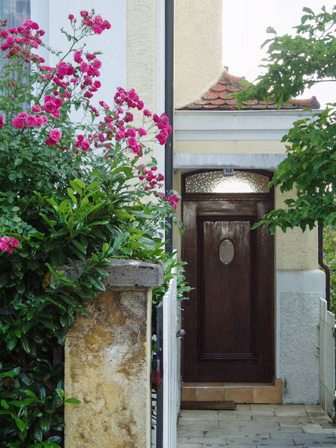 The front door of a house is surrounded by pink flowers