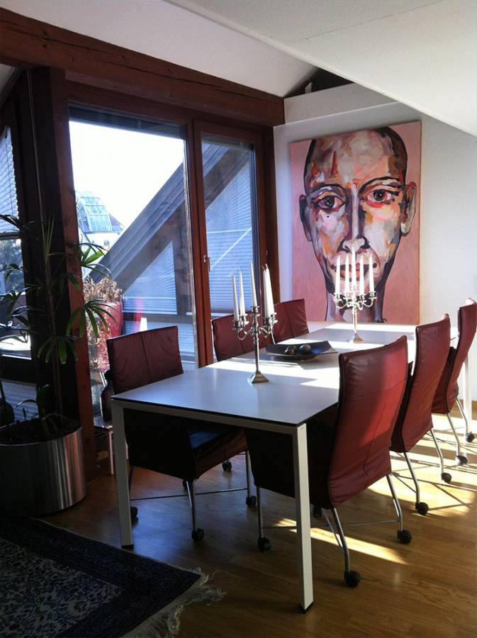 A dining room with a table and chairs and a painting on the wall