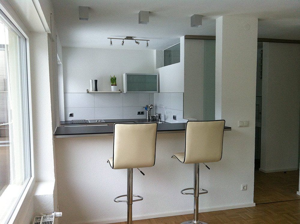 A kitchen with two bar stools and a window