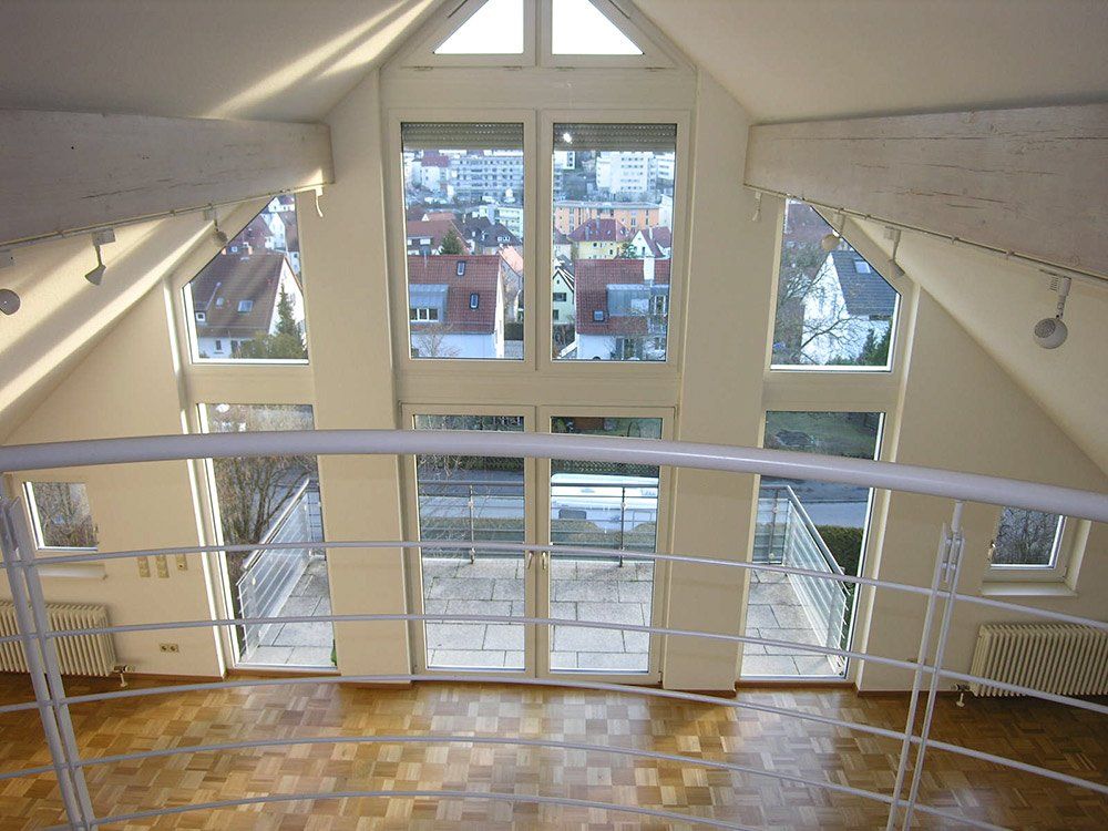 An empty room with a balcony and lots of windows