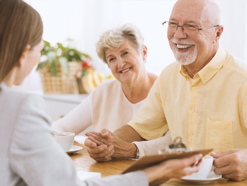 Preparing Last Will — Omaha, NE — April D. Cover Law Woman shows document to smiling elderly couple at a table; they are indoors.
