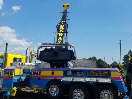 Parkway towing truck with a raised boom under a blue sky.