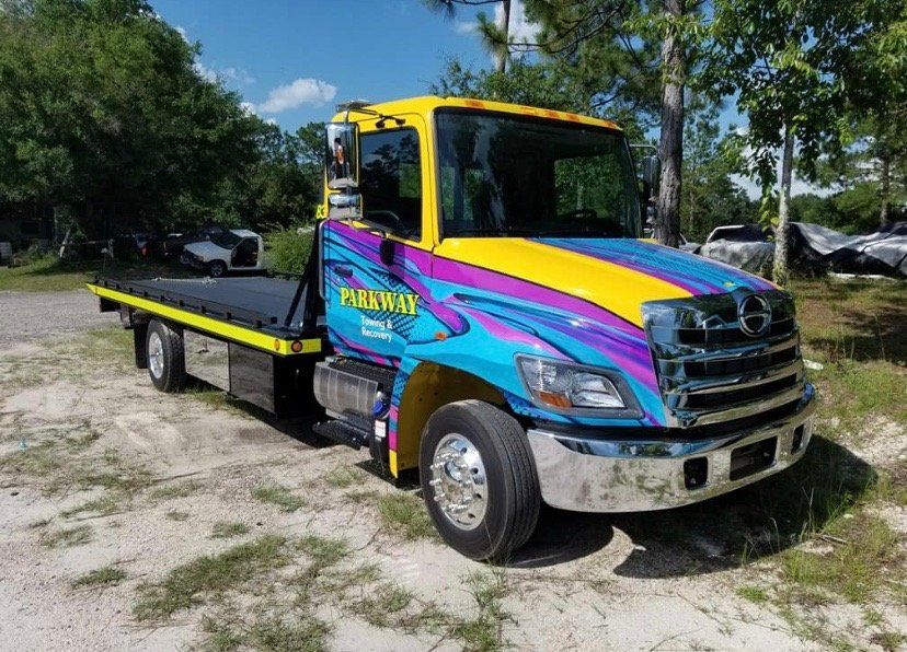Yellow and blue tow truck with colorful design parked outside.