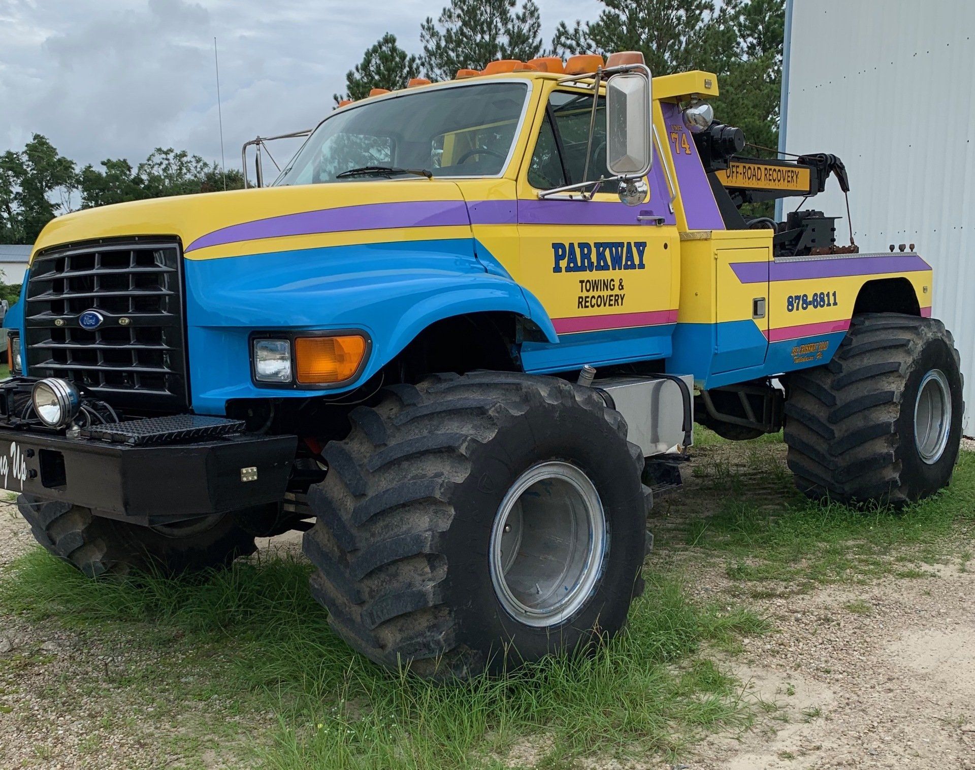 Yellow, blue, and purple monster truck tow truck with large tires.