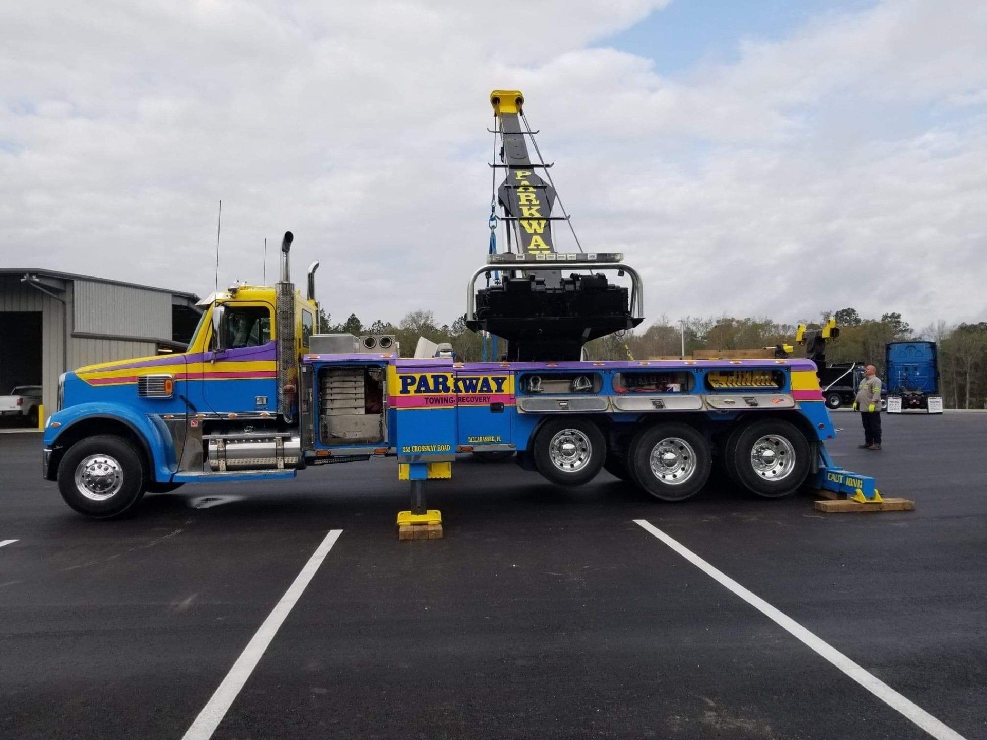 Brightly colored tow truck with extended crane, parked in a lot.