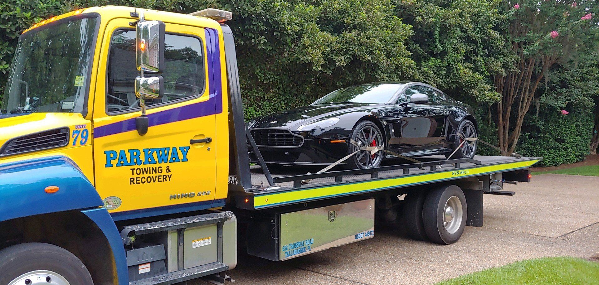 Black sports car being towed on a flatbed tow truck. Parkway Towing logo on truck.